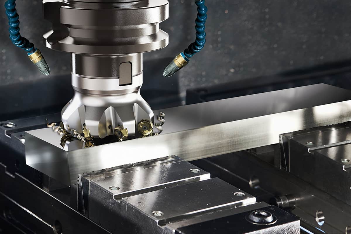 CNC fräsen lassen - Nahaufnahme einer CNC-Fräsmaschine im Betrieb, fokussiert auf die Spindel und das Schneidewerkzeug, während es ein metallisches Werkstück bearbeitet, umgeben von Metallspänen, was auf präzise Maschinenarbeit hindeutet.
